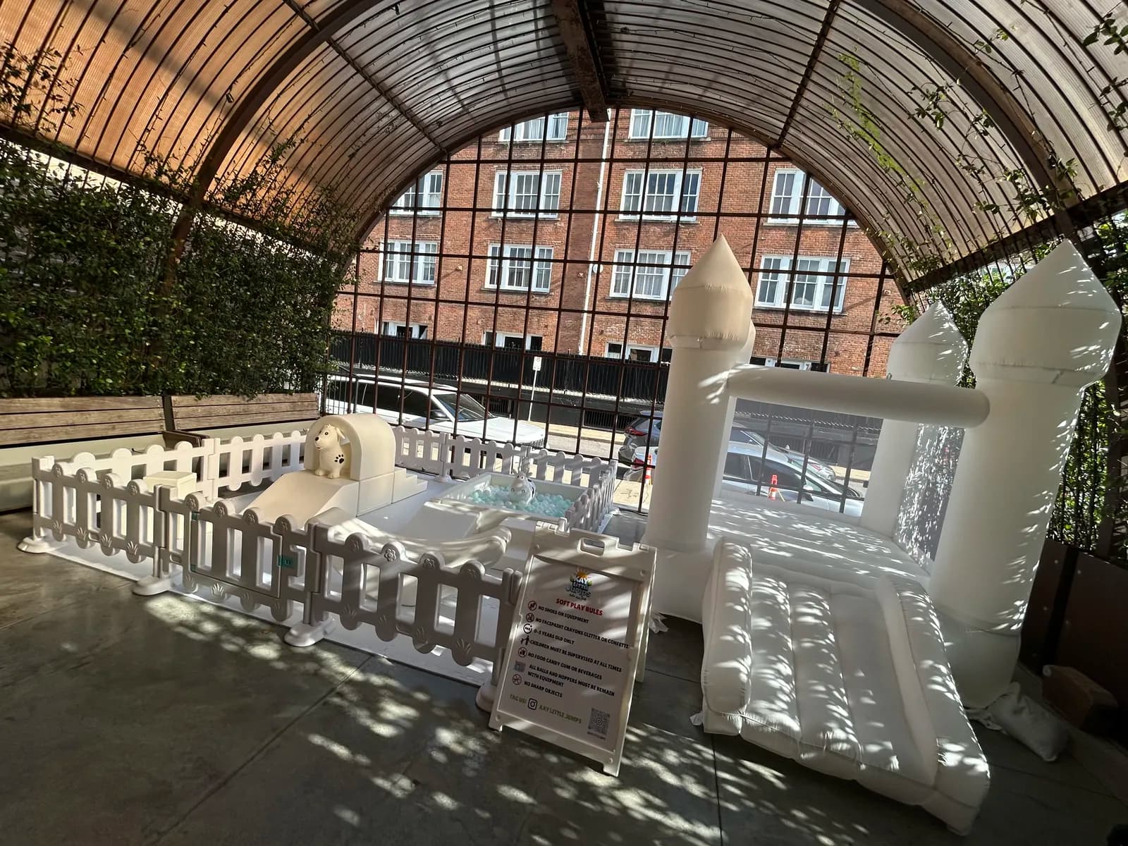 White bounce castle with picket fence set up in a glass atrium venue