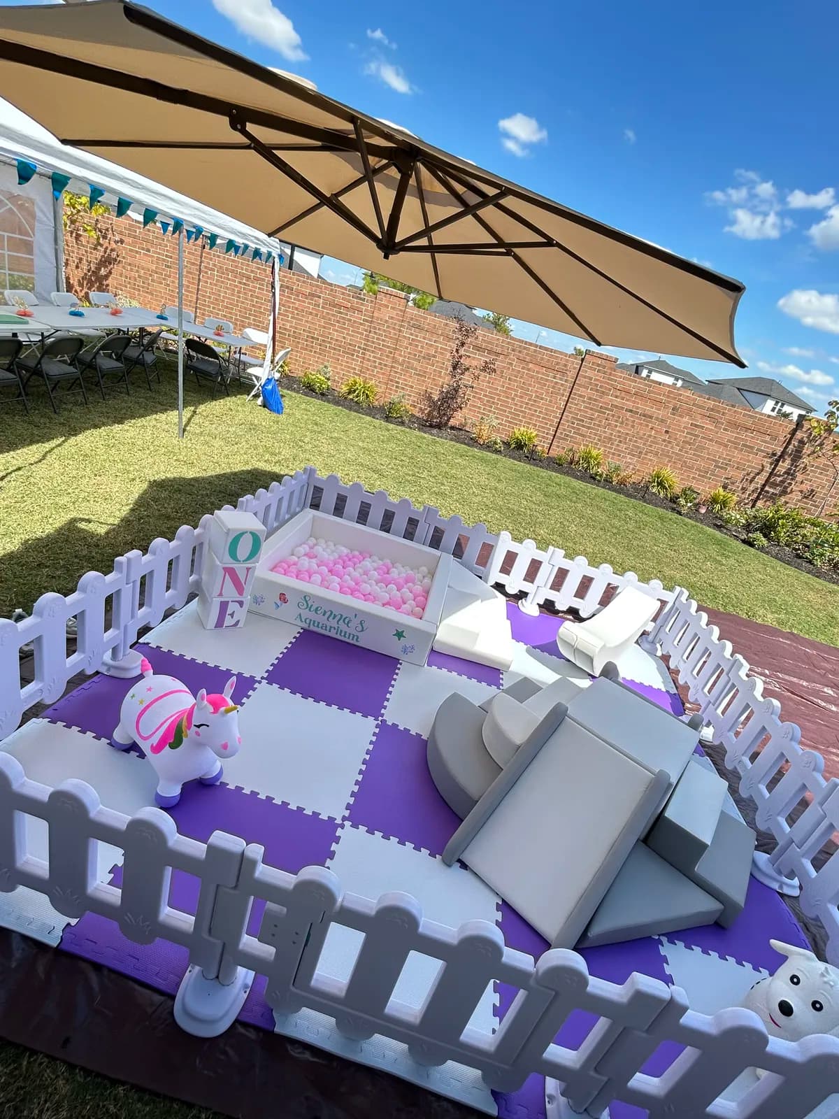 Shaded backyard soft play with purple checkered mats and a pink ball pit