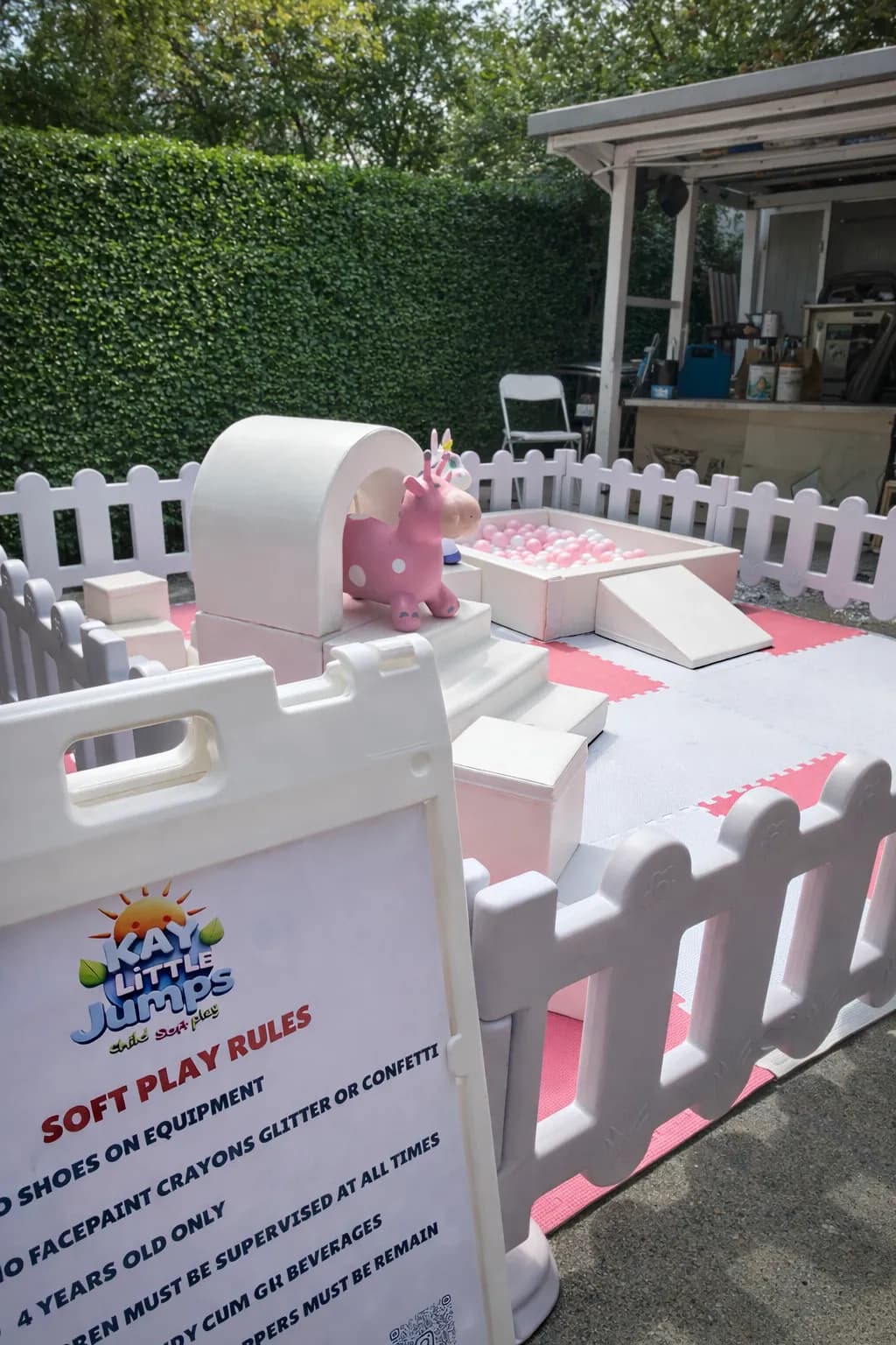 Pink and white soft play with a unicorn rocker beside the soft play rules sign
