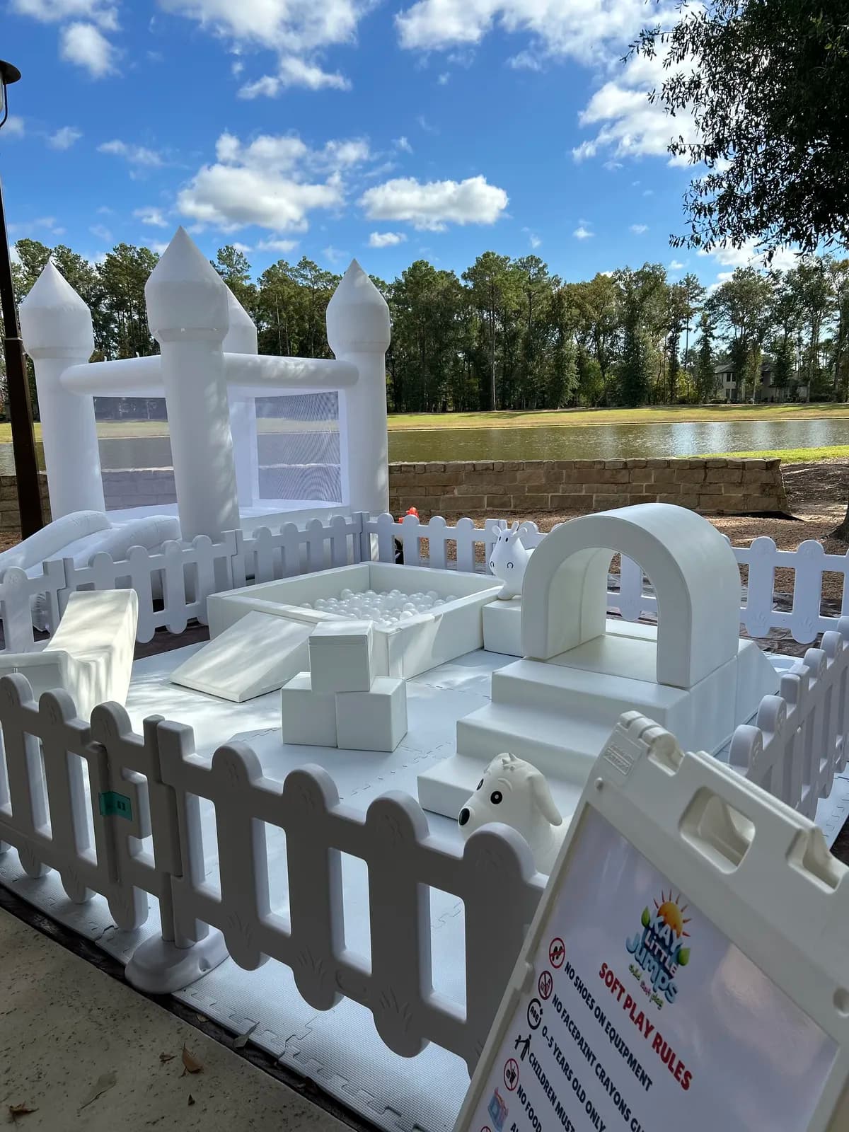 White bounce house and soft play combo set up lakeside under a blue sky